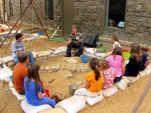 Dr. Fleming explains the archaeological artifacts to the kids.