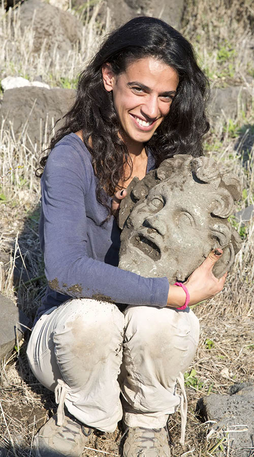 Archaeological team member cradles the mask of Pan.