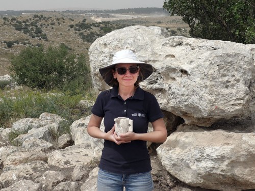 . IAA archaeologist Jenny Marcus holding a chalk cup from the time of the Second Temple period which was discovered in the estate house. Photographic credit: Avraham Tendler.
