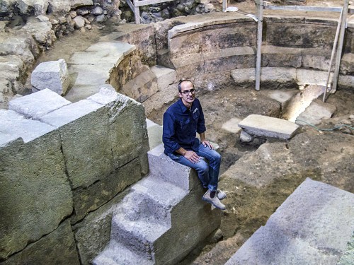 Dr Joe Uziel of the Israel Antiquities Authority, sitting on the steps of the theater structure. Photograph: Yaniv Berman, courtesy of the Israel Antiquities Authority.