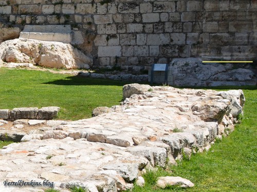 To the right of the bedrock steps that led through the outer wall you will see a section of pavement with a yellow line below it. Photo by Ferrell Jenkins.
